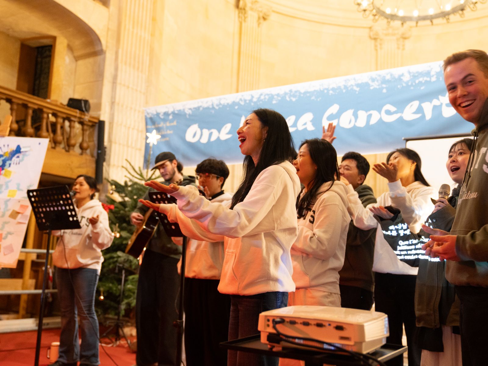 OneKorea DTS students leading worship at the One Korea Concert in Paris, hands raised, singing together on stage