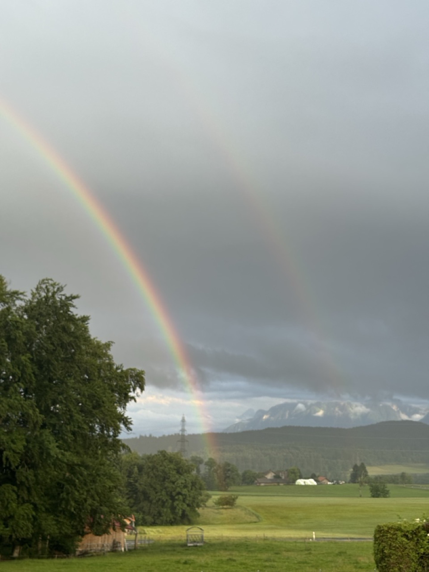 Double rainbow over the Swiss Alps and green valley fields at the YWAM base in Switzerland